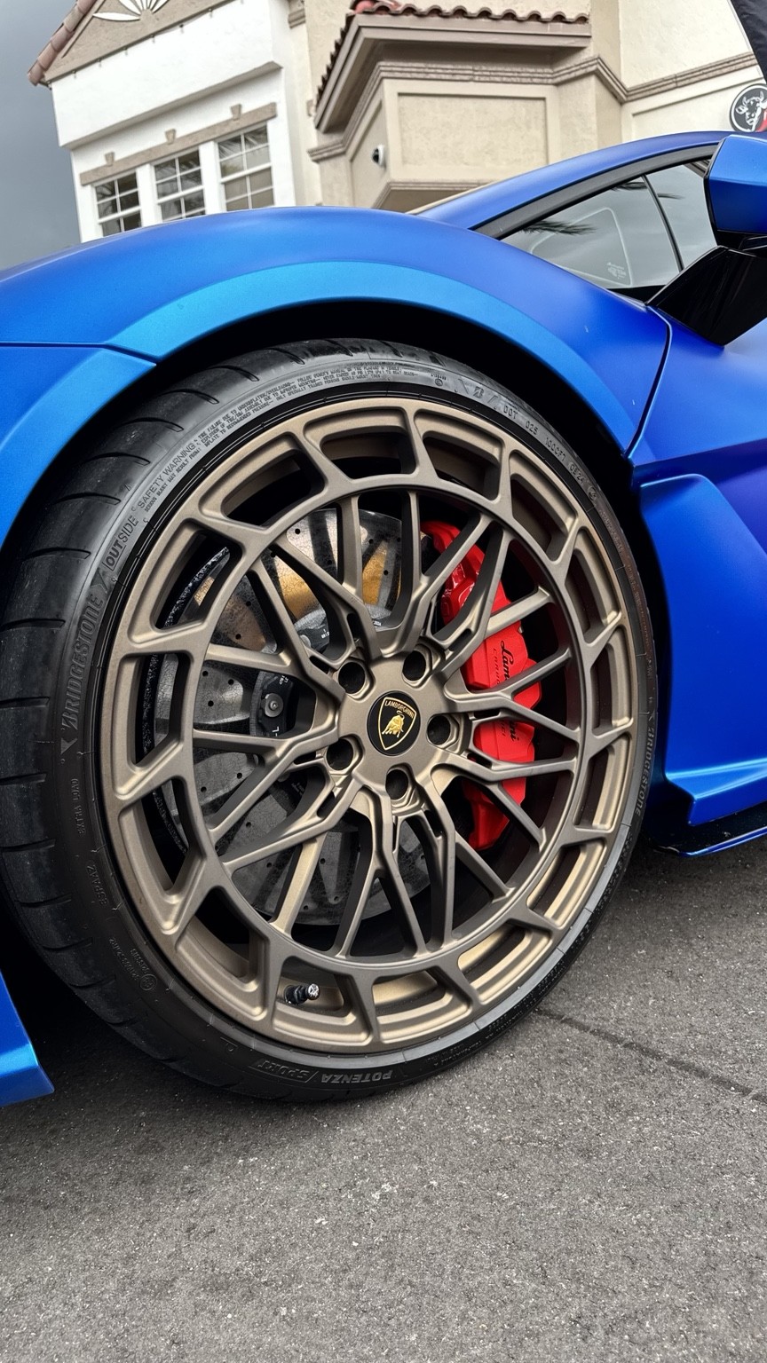 Bronze Lamborghini wheel with red brake caliper and blue bodywork